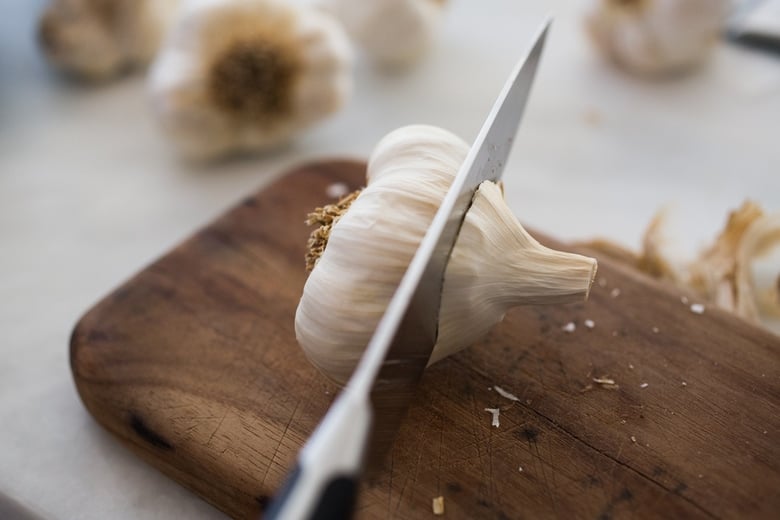 How to Roast Garlic in the oven (using whole heads of garlic or peeled garlic cloves). Roasting garlic transforms it! Spreadable, buttery, sweet, earthy, and complex it has a multitude of uses in the kitchen! And so many health benefits! Whole cloves can be stored in olive oil in the fridge for up to 10 days, or made into a paste, to add to soups, stews, sauces, dressings and mashes. #roastedgarlic #bakedgarlic #garlic #garlicbenefits #roastgarlic