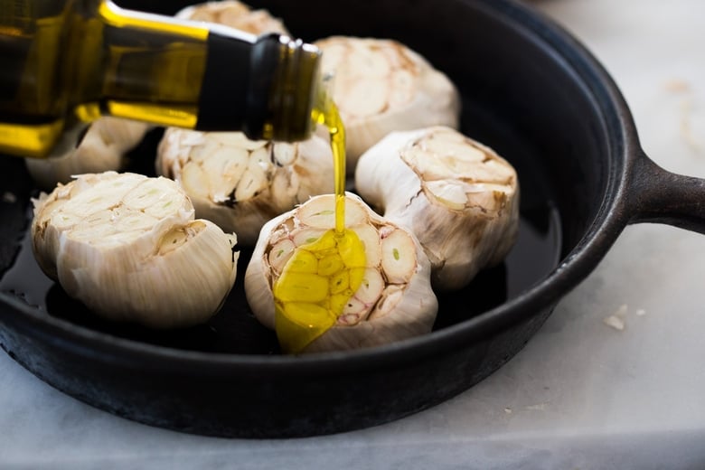 How to Roast Garlic in the oven (using whole heads of garlic or peeled garlic cloves). Roasting garlic transforms it! Spreadable, buttery, sweet, earthy, and complex it has a multitude of uses in the kitchen! And so many health benefits! Whole cloves can be stored in olive oil in the fridge for up to 10 days, or made into a paste, to add to soups, stews, sauces, dressings and mashes. #roastedgarlic #bakedgarlic #garlic #garlicbenefits #roastgarlic
