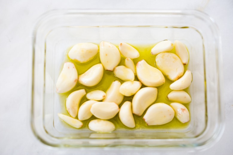 How to Roast Garlic in the oven (using whole heads of garlic or peeled garlic cloves). Roasting garlic transforms it! Spreadable, buttery, sweet, earthy, and complex it has a multitude of uses in the kitchen! And so many health benefits! Whole cloves can be stored in olive oil in the fridge for up to 10 days, or made into a paste, to add to soups, stews, sauces, dressings and mashes. #roastedgarlic #bakedgarlic #garlic #garlicbenefits #roastgarlic
