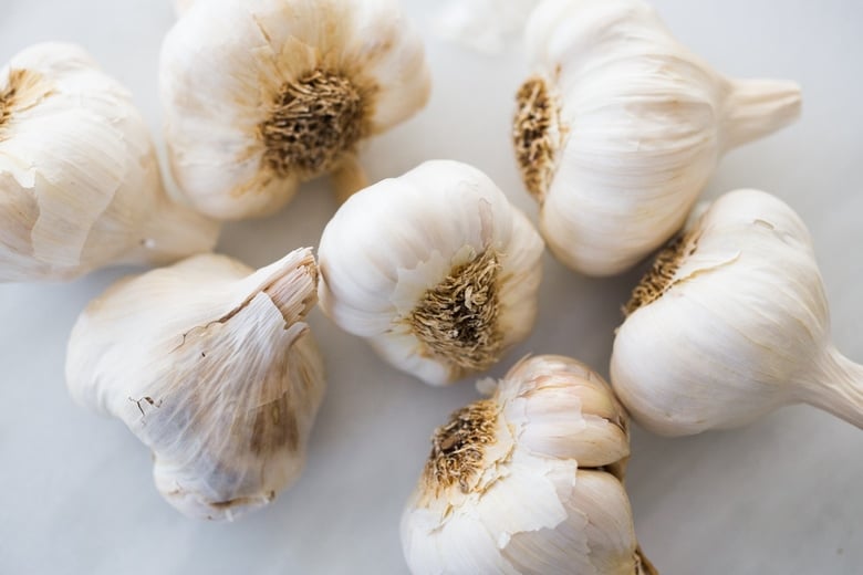 How to Roast Garlic in the oven (using whole heads of garlic or peeled garlic cloves). Roasting garlic transforms it! Spreadable, buttery, sweet, earthy, and complex it has a multitude of uses in the kitchen! And so many health benefits! Whole cloves can be stored in olive oil in the fridge for up to 10 days, or made into a paste, to add to soups, stews, sauces, dressings and mashes. #roastedgarlic #bakedgarlic #garlic #garlicbenefits #roastgarlic