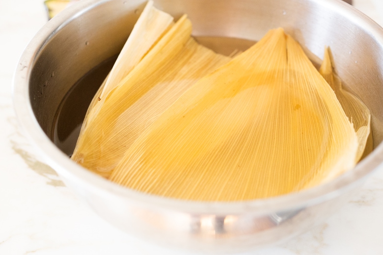 soaking the dried corn husks in hot water for tamales.