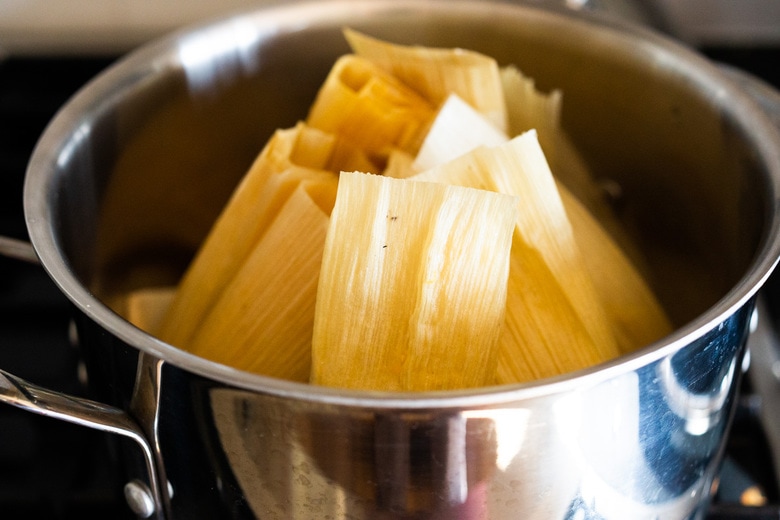 steaming tamales on the stovetop in a pot with a steamer basket. 