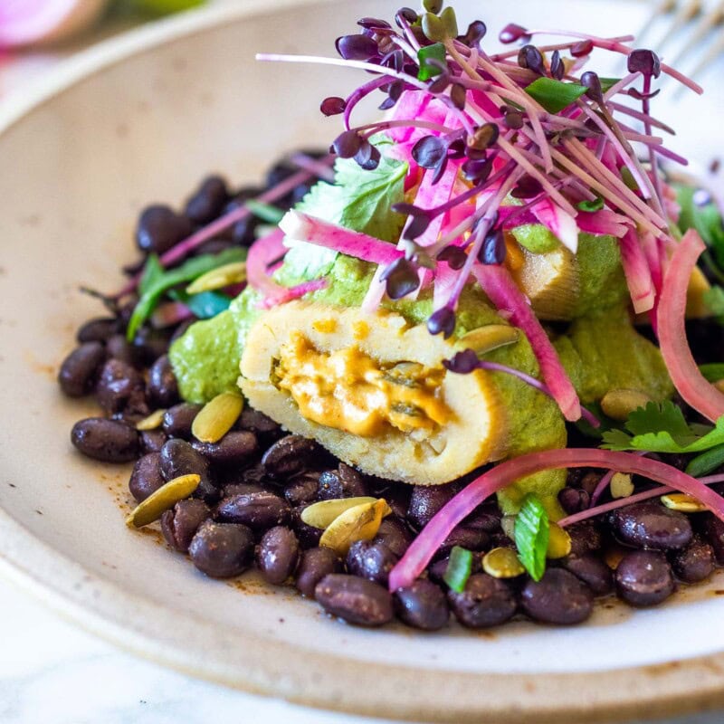 These vegetarian tamales are delicioius! Made with a creamy butternut squash filling,  topped with a flavorful poblano sauce and served over a bed of seasoned black beans, with pickled red onions. They are gluten-free and easily vegan-adaptable!