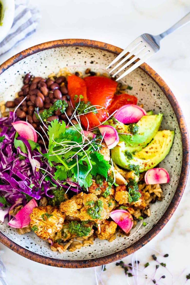 40 Mouthwatering Vegan Dinners and Plant-based Meals! | Smokey Cauliflower Chimichurri Bowls! These filling vegan bowls are full of flavor and loaded up with healthy veggies. Served over seasoned black beans (and optional rice) with Mexican Slaw, radishes, avocado, cilantro and pickled onions. #roastedcauliflower #bowls #veganbowls #veganrecipes #buddhabowls #chimichurri #eatclean #cleaneating #plantbased #healthybowls