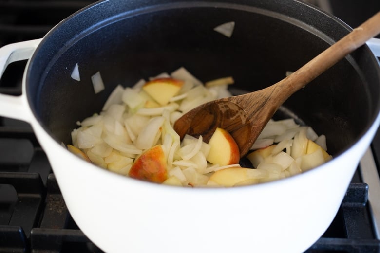 pot with onion and apples, stirred with wooden spoon. 