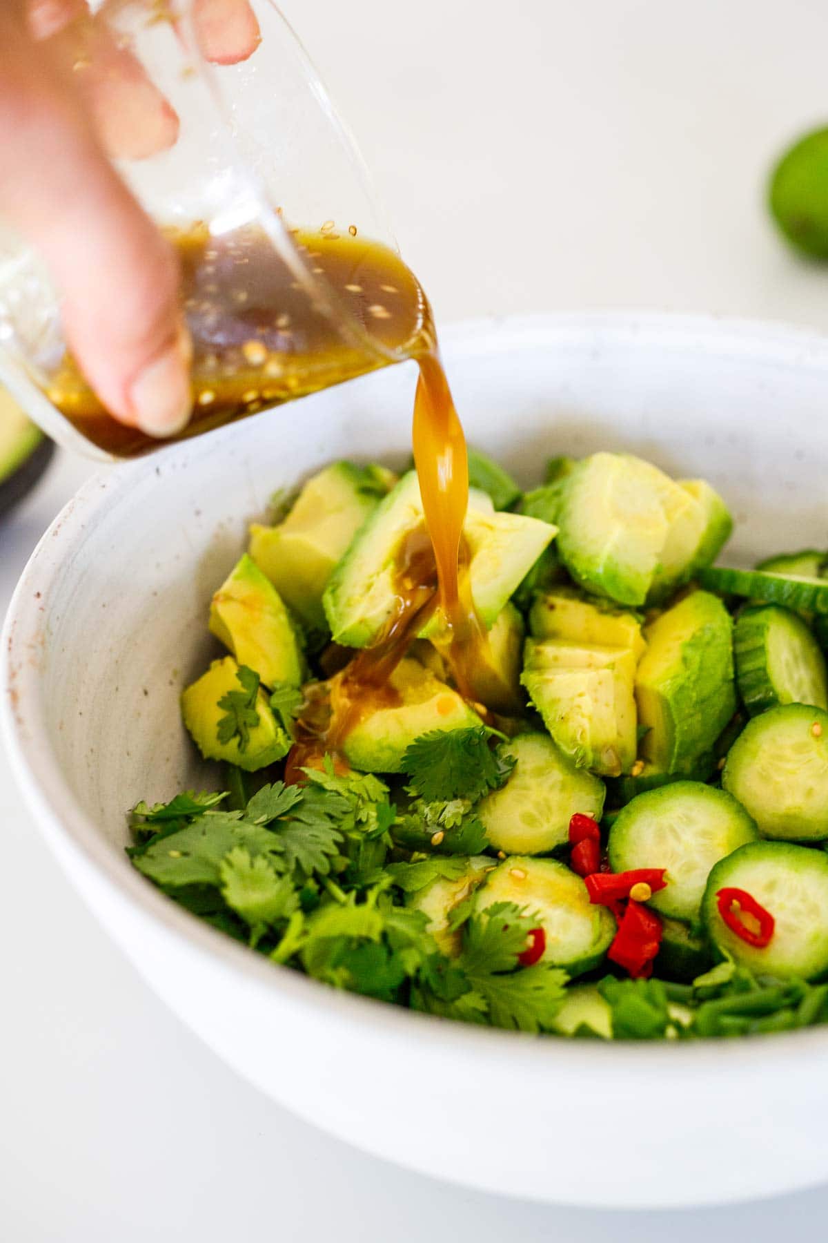 Pouring the Asian dressing in the into the salad bowl. 