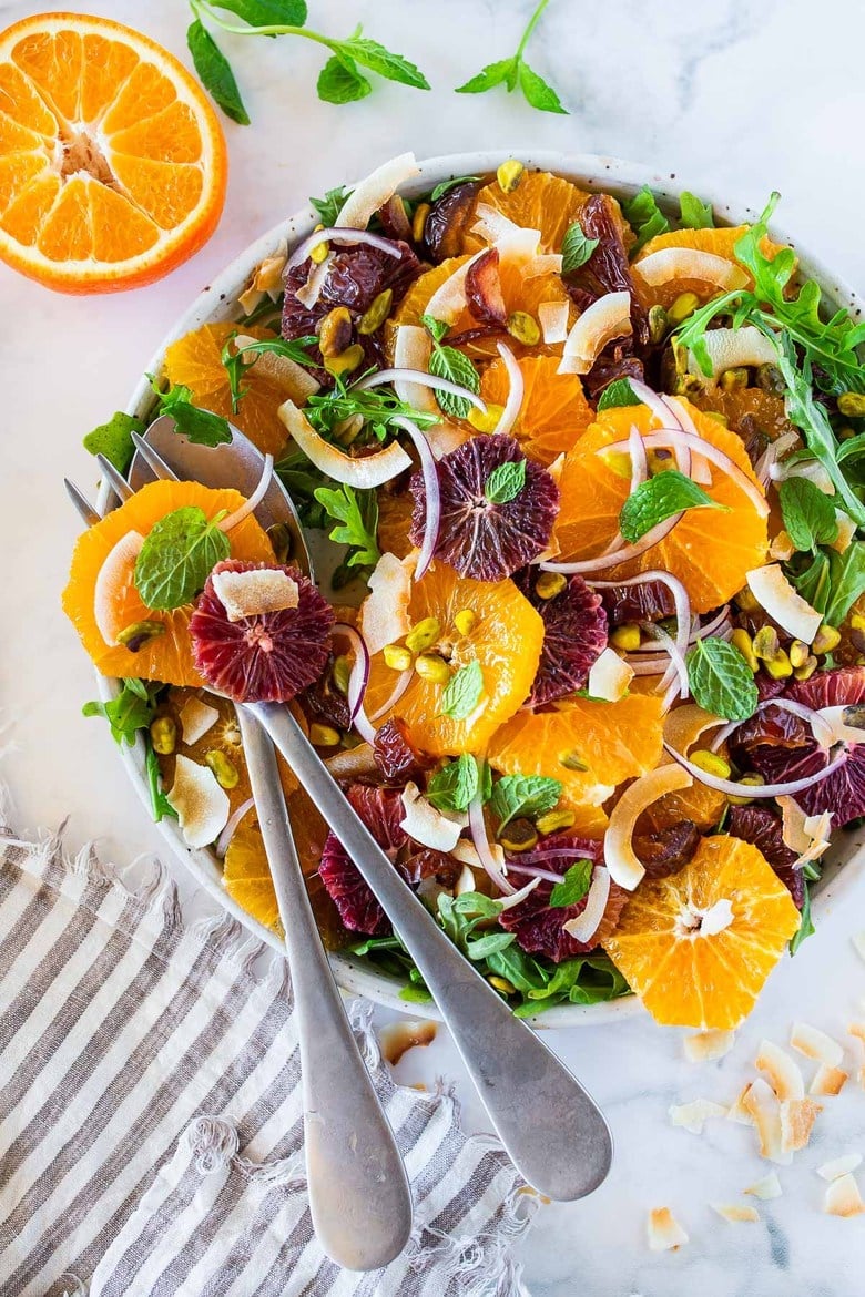 This Moroccan-inspired Citrus Salad with dates, arugula, mint, pistachios, and toasted coconut is dressed in the most flavorful Citrus Shallot Vinaigrette. It's deliciously juicy and vegan! #citrussalad #orangesalad