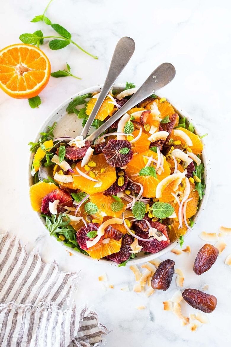 This Moroccan-inspired Citrus Salad with dates, arugula, mint, pistachios, and toasted coconut is dressed in the most flavorful Citrus Shallot Vinaigrette. It's deliciously juicy and vegan! #citrussalad #orangesalad