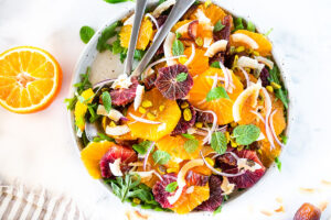 Citrus Salad with dates, arugula, mint, pistachios, and toasted coconut is dressed in the most flavorful Citrus Shallot Vinaigrette. It's deliciously juicy and vegan! #citrussalad #orangesalad