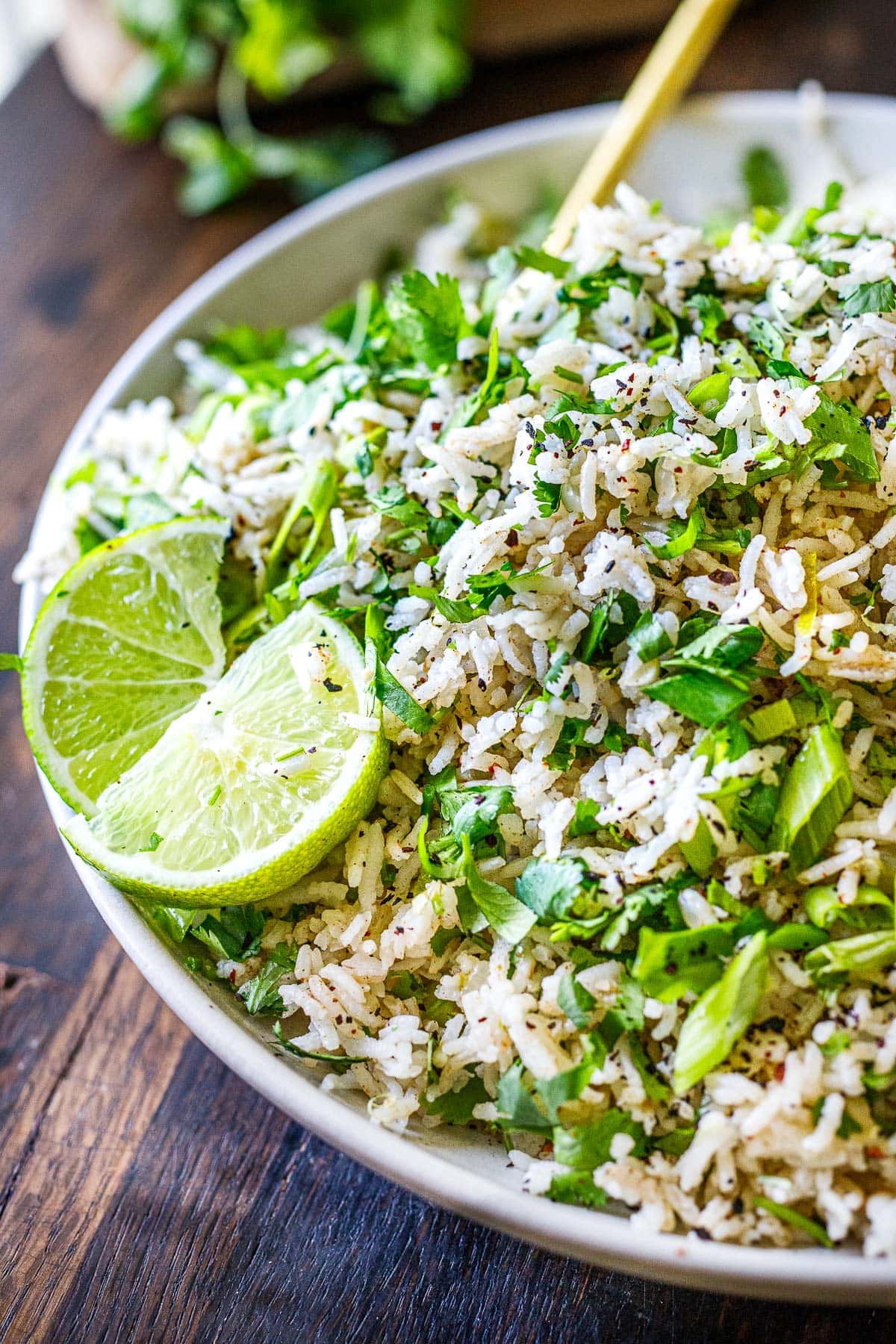 Cilantro lime rice with green onions and limes on a serving platter. 