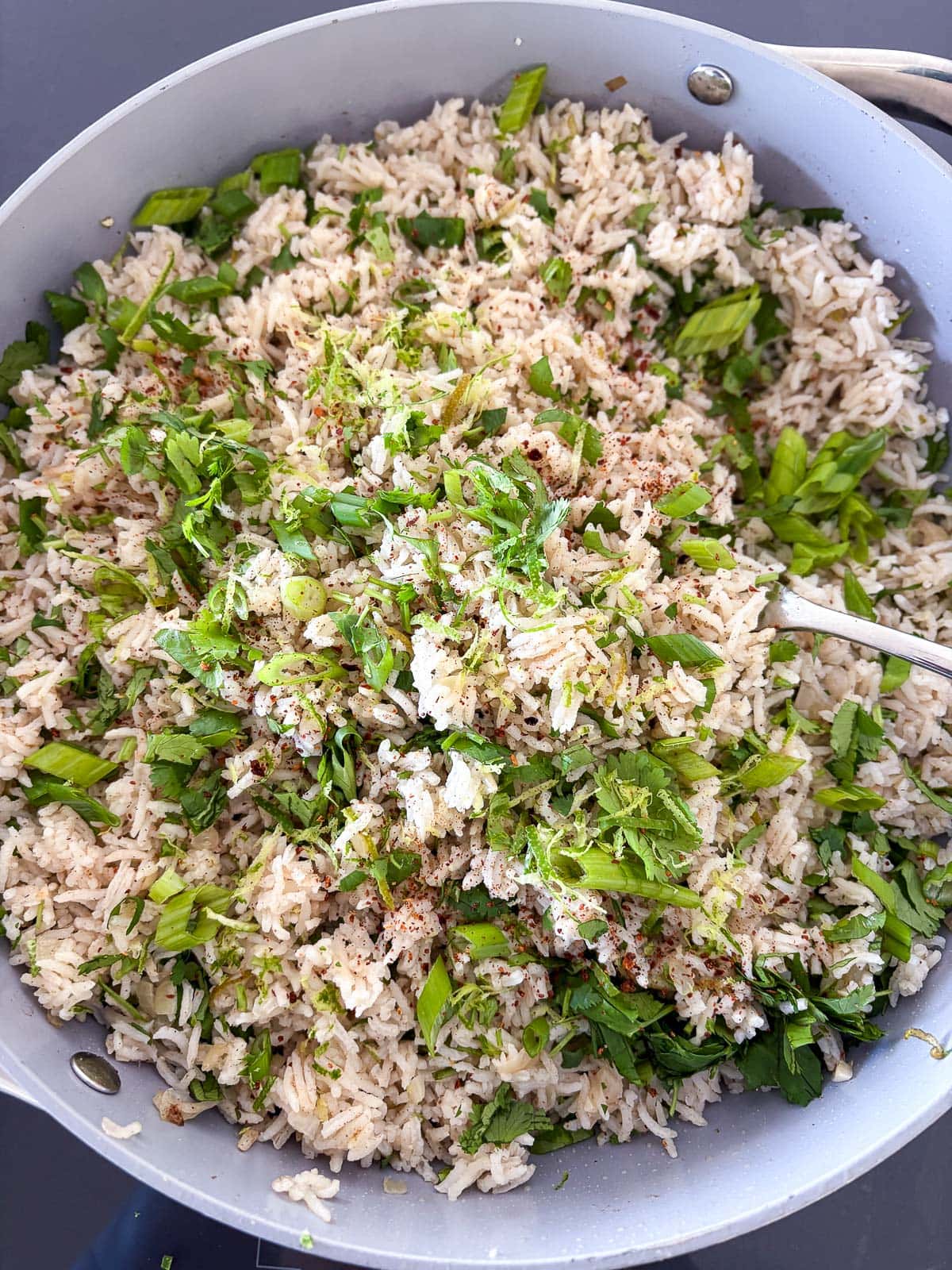 Fluffing the rice and adding cilantro, green onions and lime.