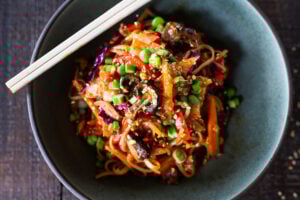 Here's a super tasty recipe for Vegan Kimchi Noodles, stir-fried with lots of healthy veggies you probably have on hand. Keep it vegan or add an egg, chicken or shrimp! Crispy tofu is also a delicious option here! #kimchi #kimchinoodles #kimchirecipes #vegannoodles