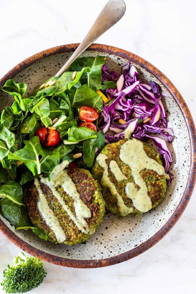 Broccoli Quinoa Cakes with a creamy herbs sauce and salad on a plate. 