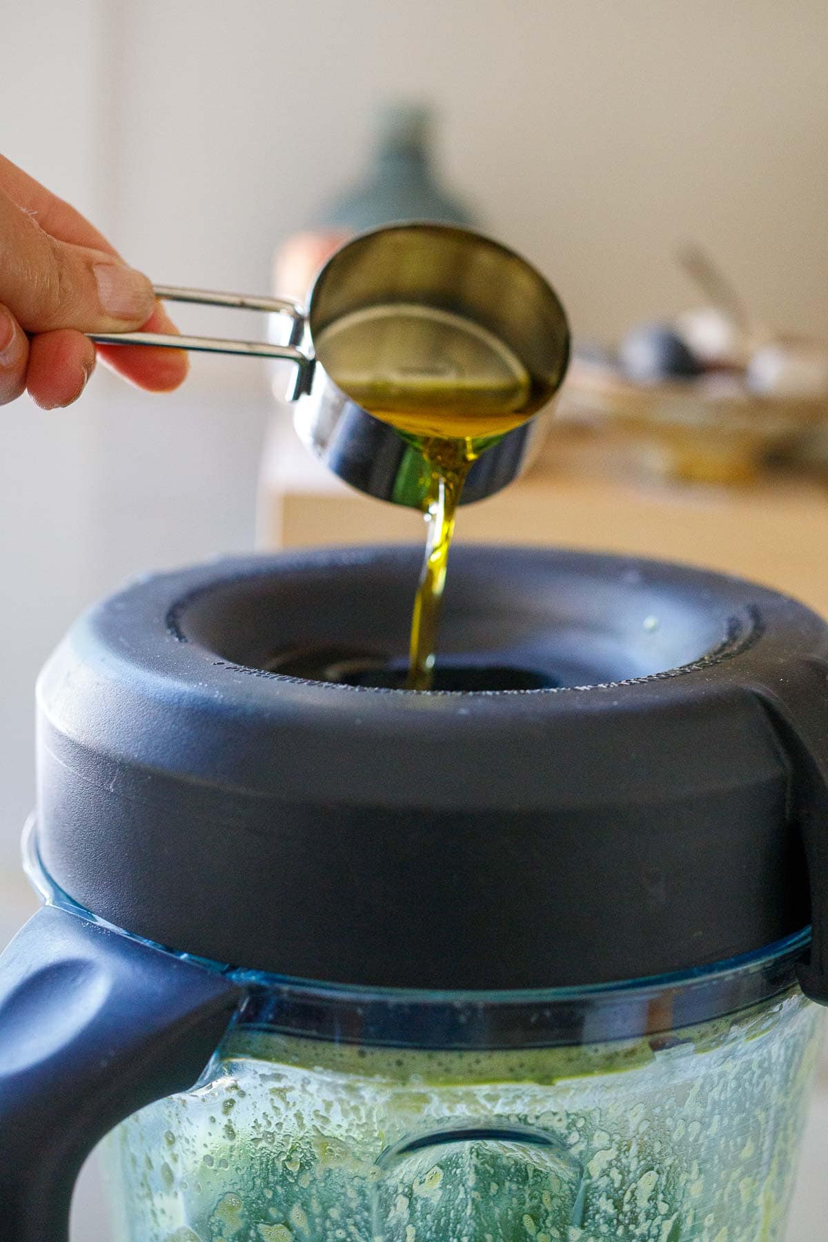 Drizzing in the olive oil to the blender.