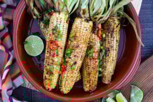 This Indian Masala Street Corn hails from the streets of Bombay. It's lathered with ghee and garam masala spice- a simple easy summer side dish to add to your next Indian feast! #grilledcorn #masalacorn #indiancorn