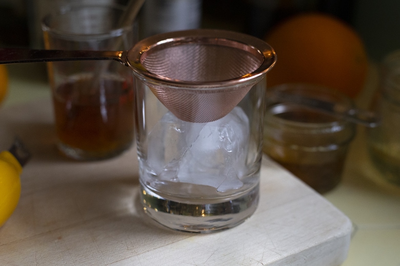 straining the cocktail over ice. 