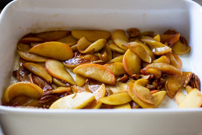 sautéed apples and pecans spread out in base of casserole dish.