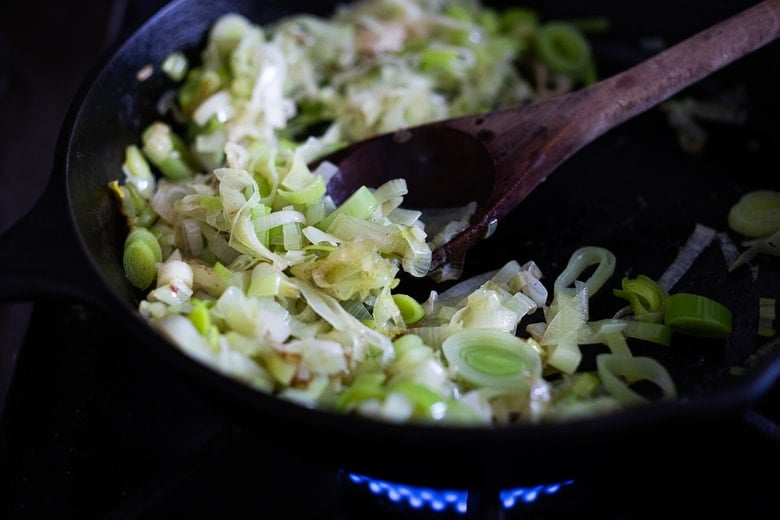cast iron skillet with sauteed leeks and wood spoon. 