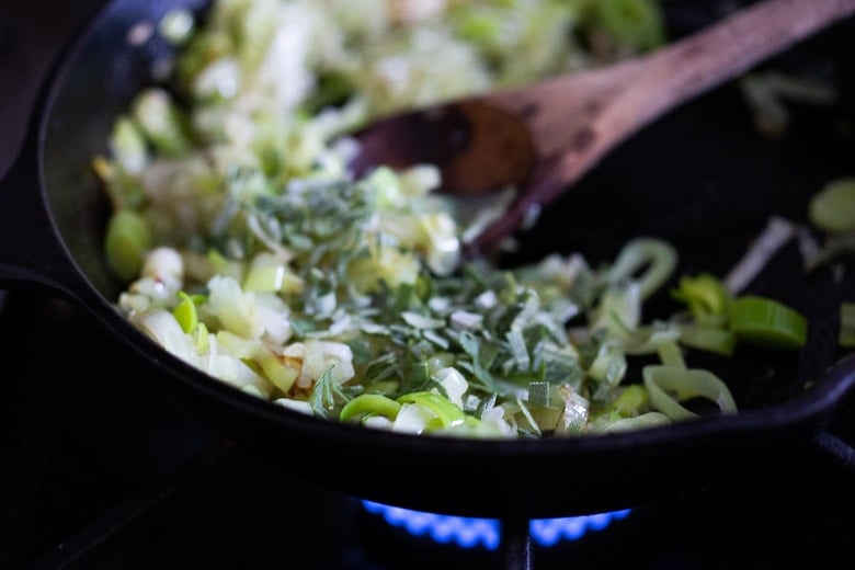 freshly chopped sage added to cast iron skillet with leeks. 