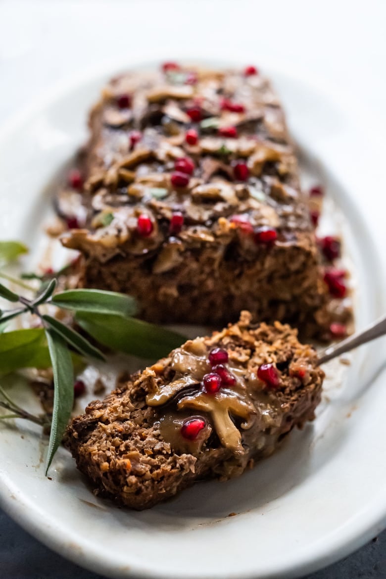 mushroom loaf topped with mushroom gravy and pomegranate seeds, with slice cut off. 