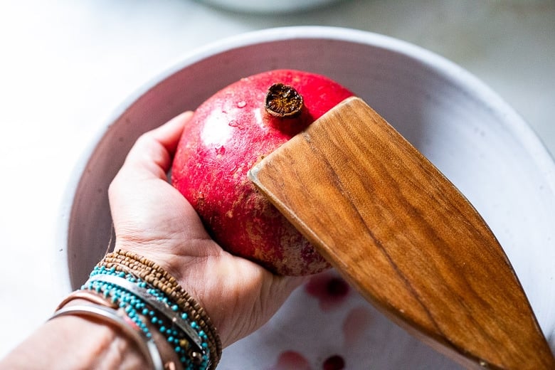 whack the pomegranate with a wood spoon facing down into a bowl 