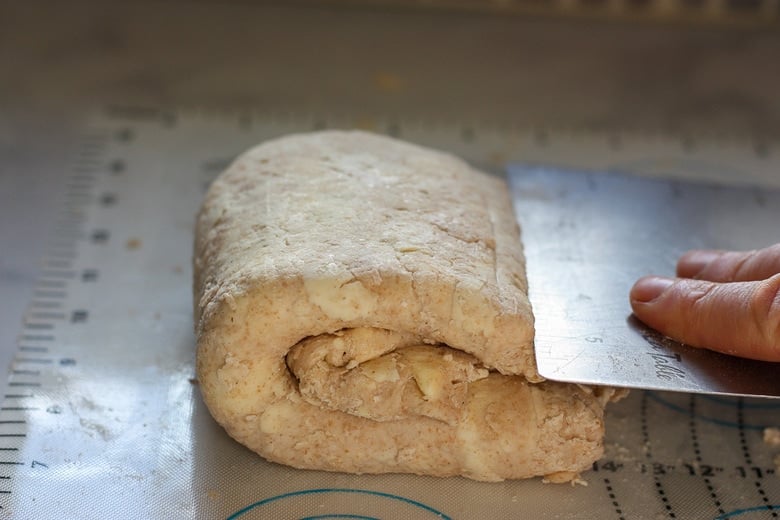 using a bench scraper to fold the galette dough.