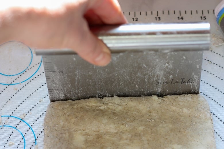 using a bench scraper to square up the sides of the galette dough.