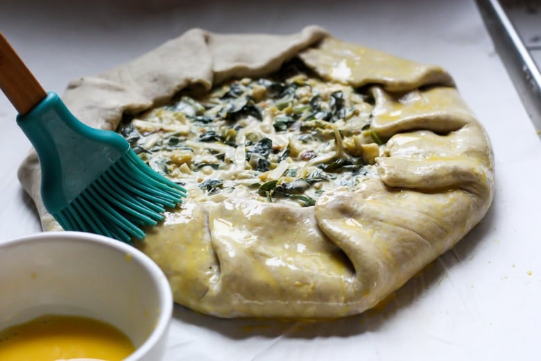 brushing egg wash over folded galette.