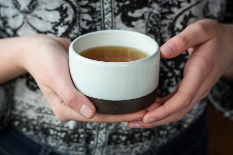 A cup of herbal tea in hands.