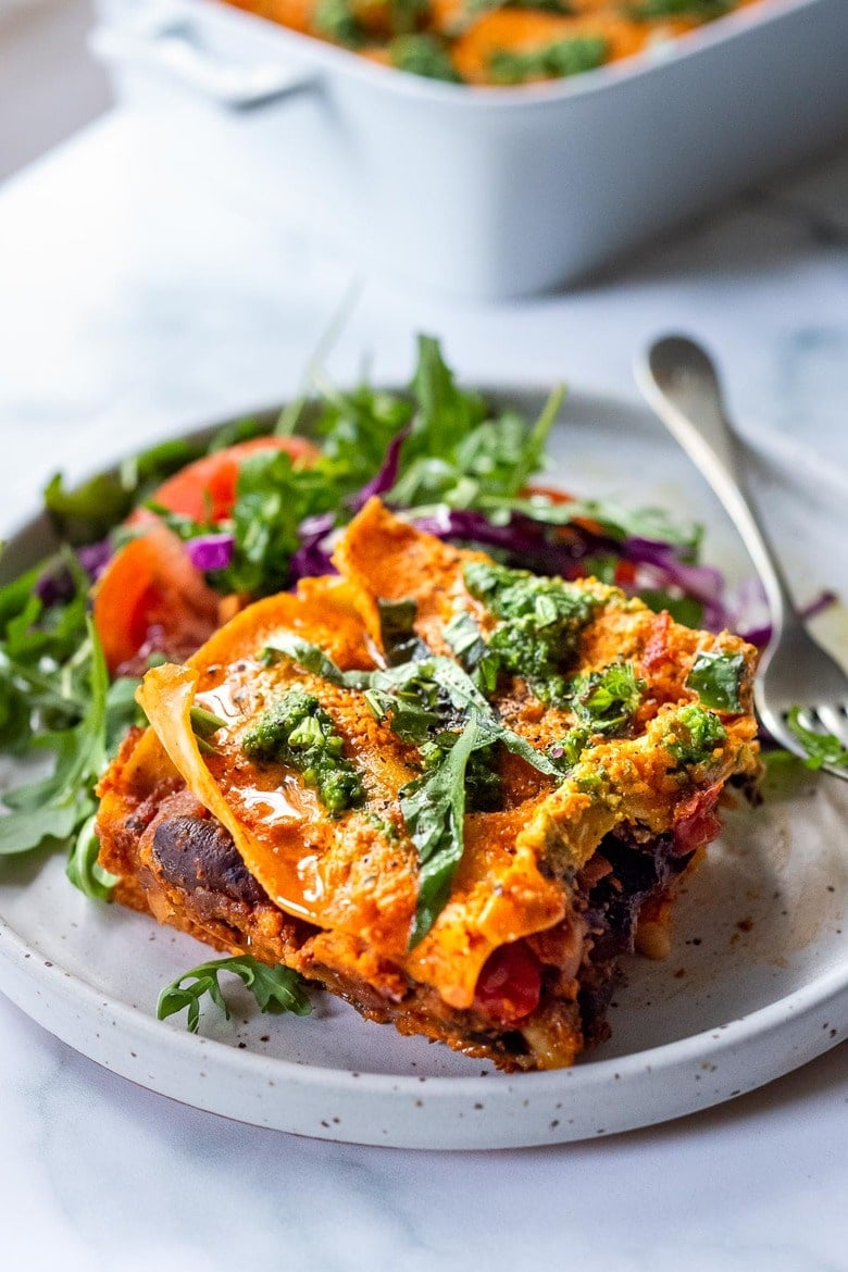 This Vegan Lasagna is made with a robust mushroom-spinach bolognese sauce, fresh basil, vegan ricotta and no-boil lasagna noodles, topped off with a creamy marinara sauce, drizzled with Arugula Basil Pesto. Vegan comfort food at its best! #veganlasagna #vegandinnerrecipes #vegan #lasagna #mushroombolognese