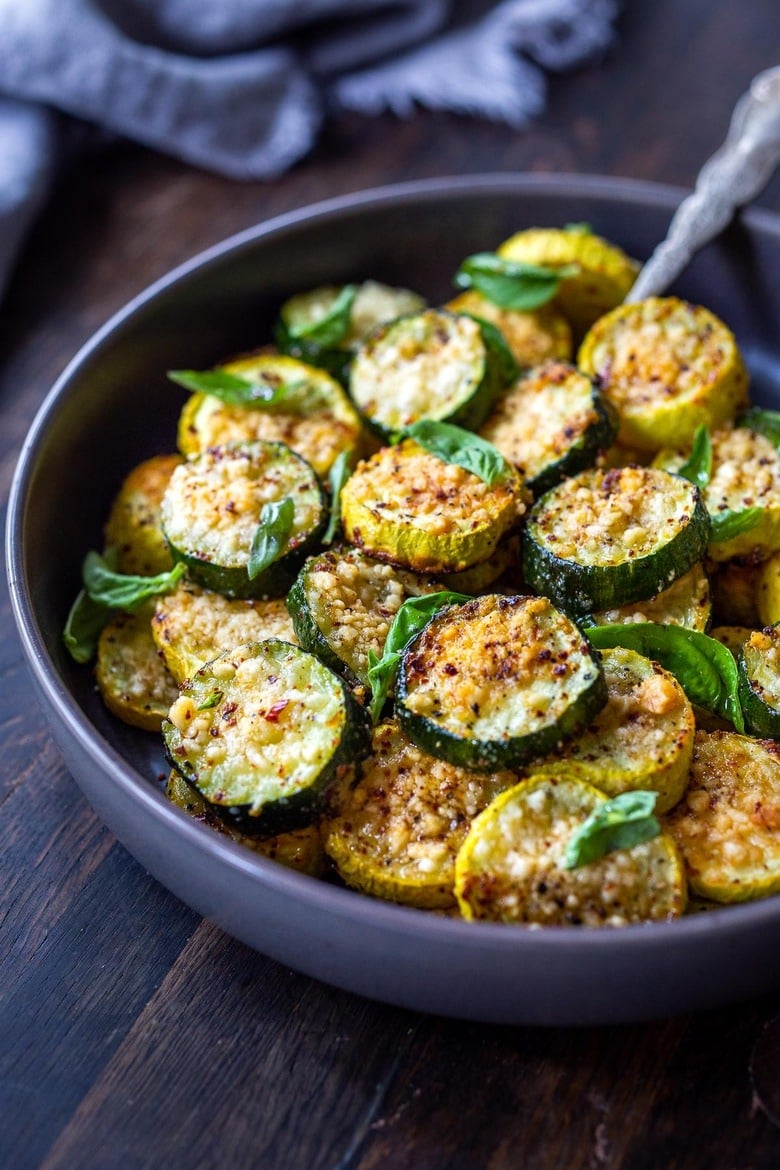 bowl of crispy baked zucchini with pecorino topped with basil.
