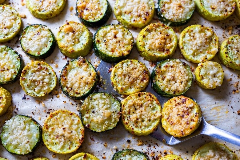 crispy and golden baked zucchini with pecorino on baking sheet with metal spatula.