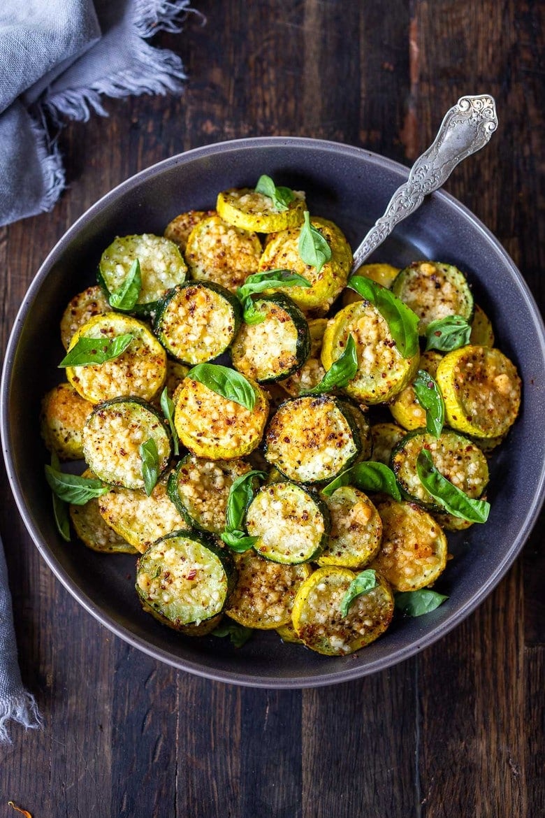 bowl of baked zucchini with pecorino garnished with basil.