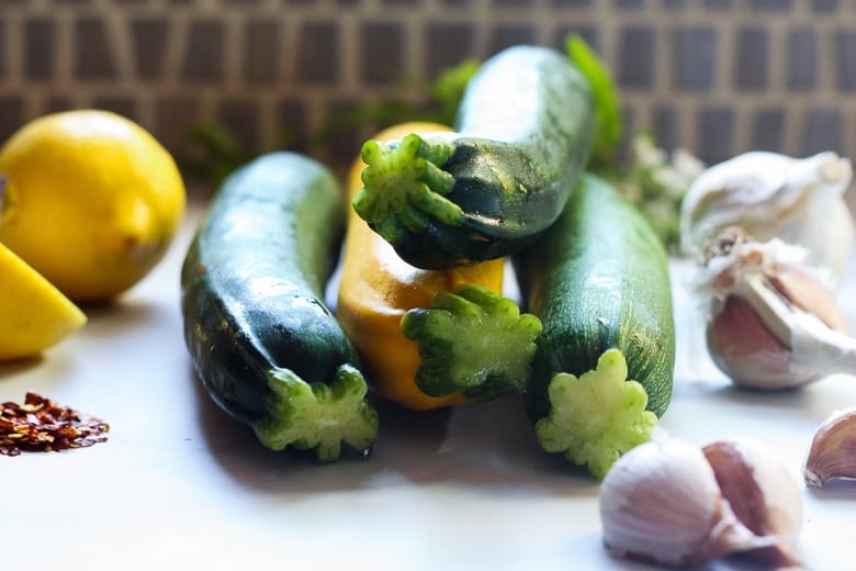 zucchini, garlic and lemons on counter, ingredients to make zucchini ribbons.
