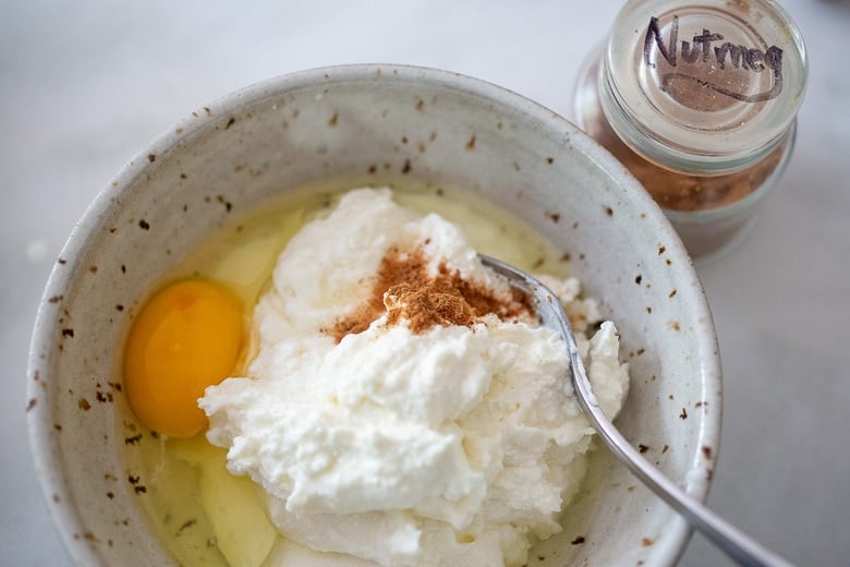 ricotta, nutmeg and and egg in a bowl about to be mixed.