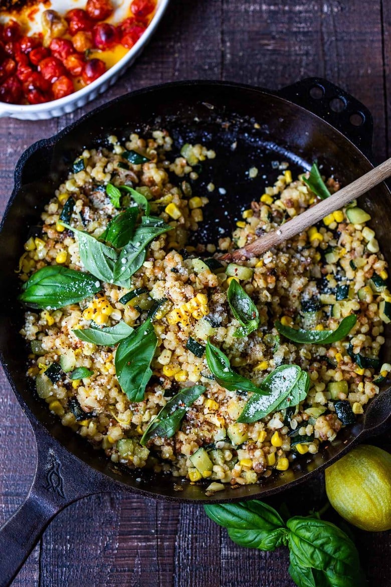 large cast iron skillet with fregola sarda with corn, zucchini and basil.