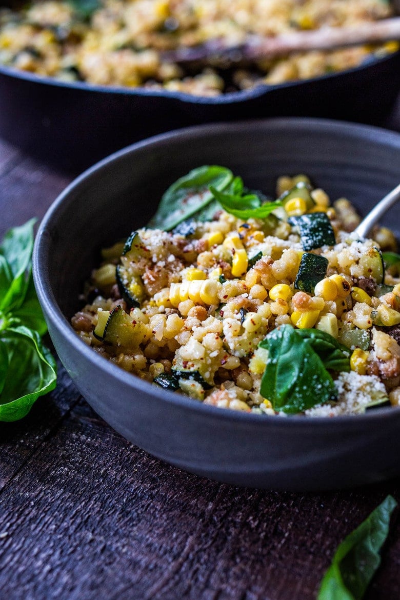 fregola sarda with corn and zucchini, pecorino and basil in bowl.