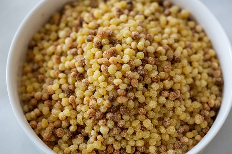toasted handmade fregola sarda pasta in bowl.