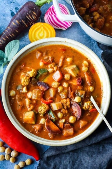 This Harvest Vegetable Soup recipe is so cozy and nourishing! Packed with seasonal veggies and chickpeas in a luscious roasted tomato base with fresh herbs. Vegan & delicious!