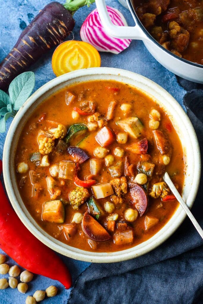 This Harvest Vegetable Soup recipe is so cozy and nourishing! Packed with seasonal veggies and chickpeas in a luscious roasted tomato base with fresh herbs. Vegan & delicious!