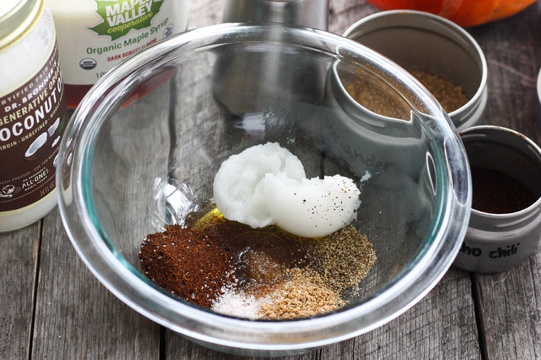 glass bowl with coconut oil, ancho chili powder, coriander, salt, pepper, and maple syrup.