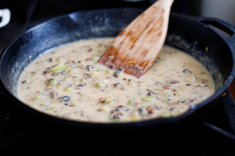 creating the thick "gravy" for the veggie pot pie in a skillet - wood spatula stirring almond milk, celery, onions.