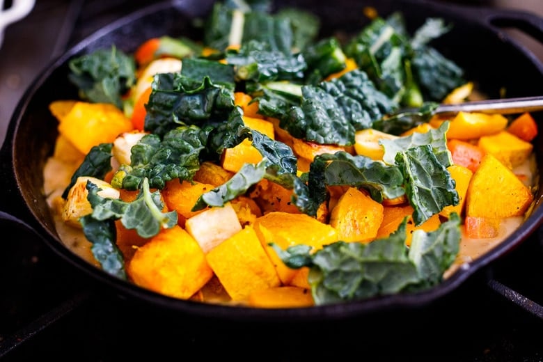 folding in the roasted veggies and kale into the stew base.