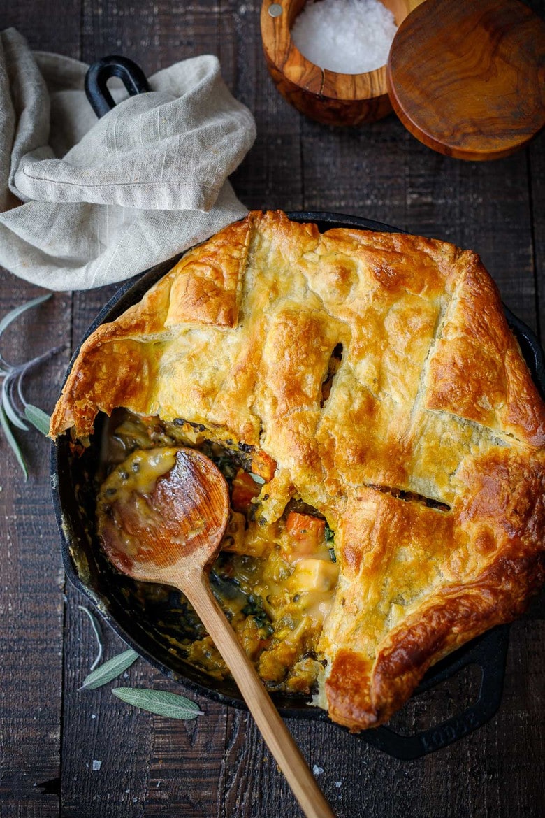 cast iron skillet with lentil pot pie with butternut squash - and wood spoon in the dish.