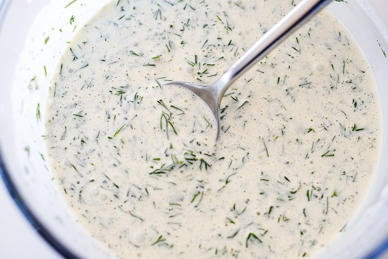 whisking the ranch dressing in a glass bowl.