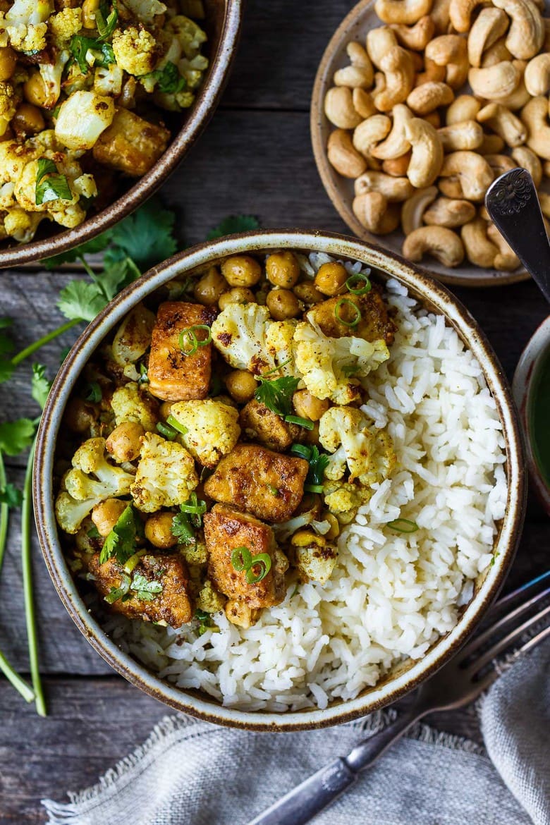 Savory oven-roasted Indian Cauliflower, Chickpea, and Tofu Bowls served over fluffy basmati rice with Cilantro Mint Chutney, seasoned with a simple Madras Curry dressing. A simple dish rich with fragrant spice and amazing flavor. Healthy, flavorful, and vegan! (Updated 4/22)