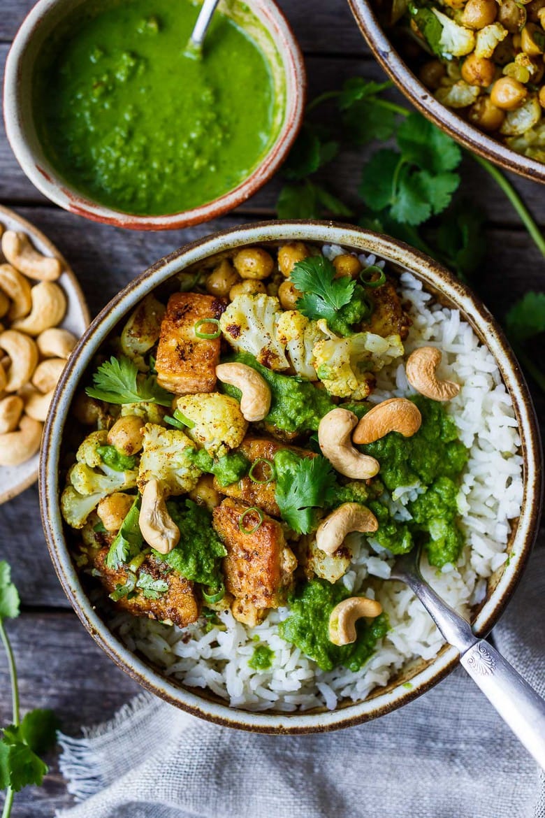 Savory oven-roasted Indian Cauliflower, Chickpea, and Tofu Bowls served over fluffy basmati rice with Cilantro Mint Chutney, seasoned with a simple Madras Curry dressing. A simple dish rich with fragrant spice and amazing flavor. Healthy, flavorful, and vegan! (Updated 4/22)