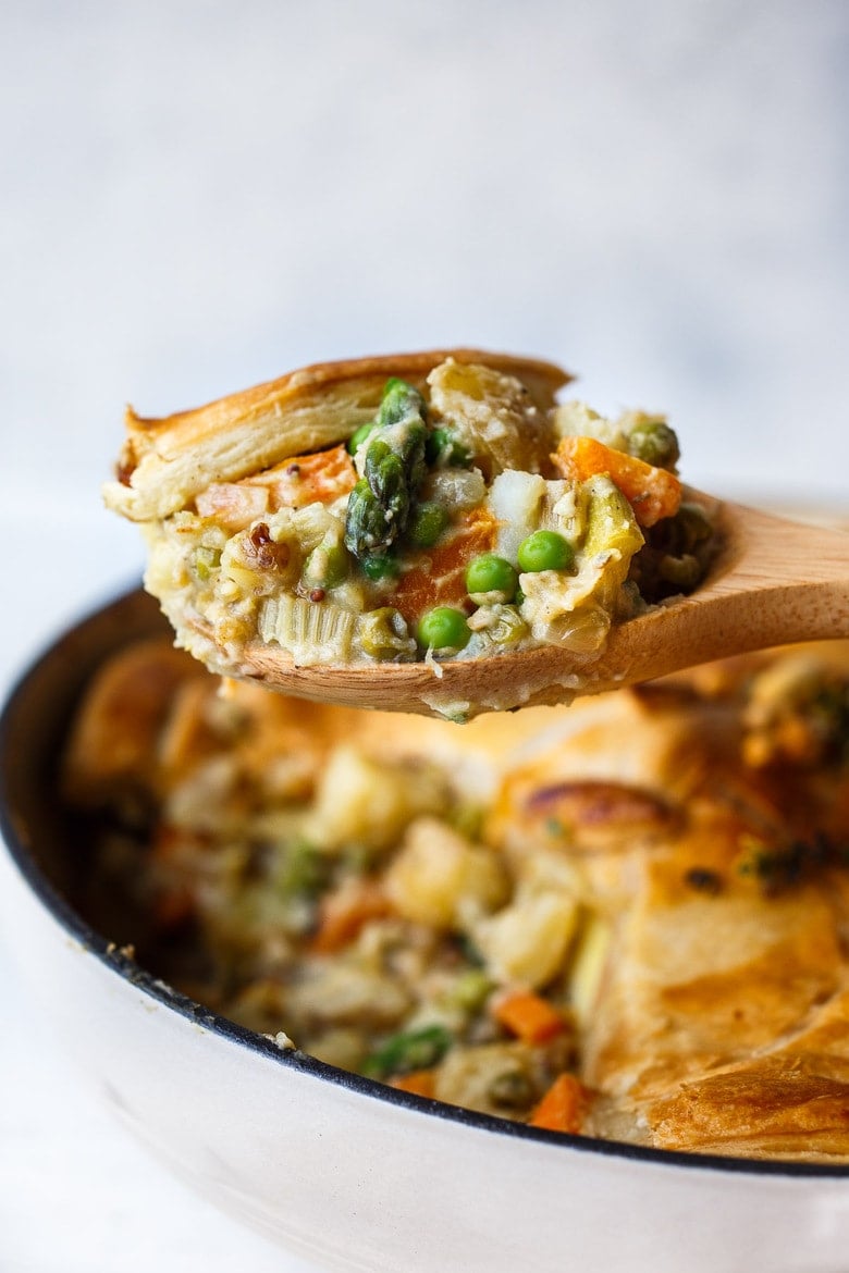 A scoop of vegetable pot pie on a wooden spoon. 