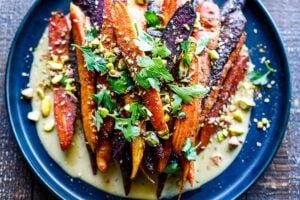 A quick and easy recipe for Roasted Carrots with cumin and coriander seeds, over a creamy Maple-Tahini Sauce, sprinkled with Pistachios and Dukkha, a tasty vegan side dish that pairs with many things.