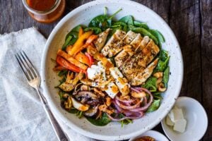 This spinach salad is a twist on the classic with deeply flavored with grilled mushrooms, red onions, sweet peppers and herby grilled chicken. Topped with our flavorful take on a healthy French style dressing. A perfect complete dinner for warm days.